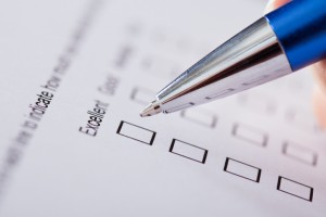 Close-up Of Hand Holding Pen Over Survey Form